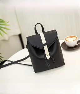 Detail of a mini black leather backpack with white stripe and gold buckle in a cafe setting