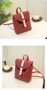 Close-up of red vintage mini backpack with ivory strap and gold buckle on a white table