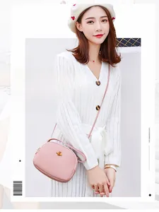 Détail du sac bandoulière rose avec boucle abeille dorée sur robe en tricot