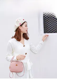 Petit sac bandoulière rose avec abeille dorée porté par un mannequin en extérieur