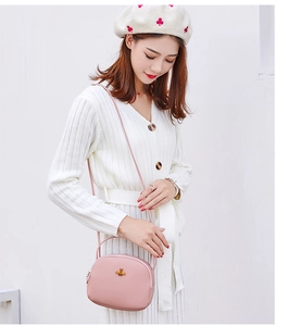 Gros plan sur un sac bandoulière rose avec boucle d'abeille dorée sur cuir lisse