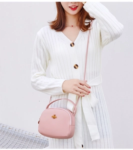 Vue détaillée du mini sac rond rose à bandoulière avec abeille dorée et poignée chic
