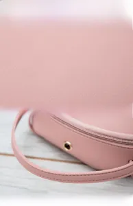 Détail de la texture en cuir PU rose et des doubles poignées d'un sac bandoulière