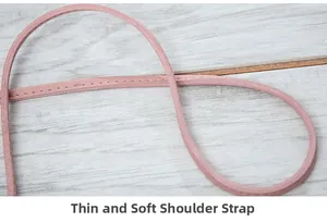 Gros plan d'une fine bandoulière en cuir rose avec surpiqûres détaillées sur bois