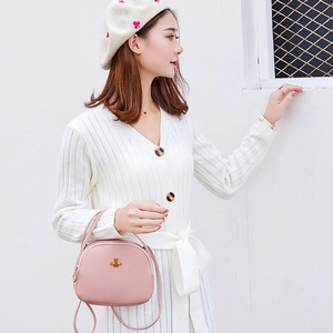 Sac bandoulière demi-lune rose avec emblème d'abeille en métal porté par un mannequin