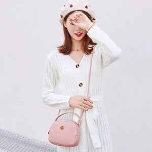 Détail d'un mini sac bandoulière rose avec ornement abeille dorée et double fermeture