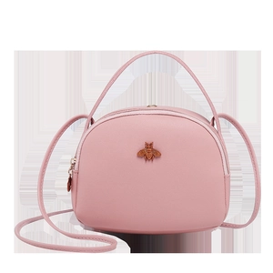 Vue détaillée du petit sac rond rose avec emblème d'abeille dorée et poignée supérieure