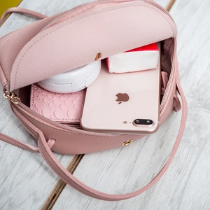 Sac bandoulière rond rose montrant l'espace intérieur pour téléphone et accessoires