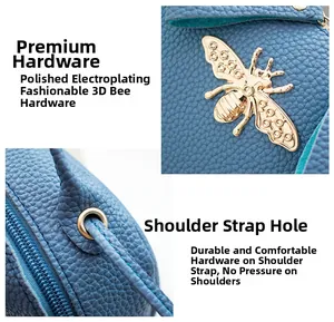 Details einer blauen Lederhandtasche mit goldener Biene und polierten Metallringen