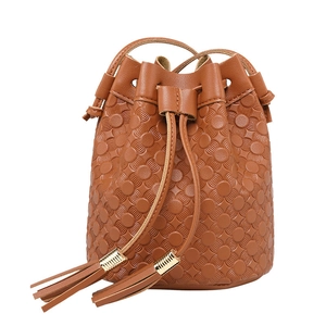 Brown bucket bag with floral embossing and decorative tassels on white background