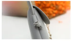Detail shot of grey mini bag featuring neat precision stitching and knotted shoulder strap