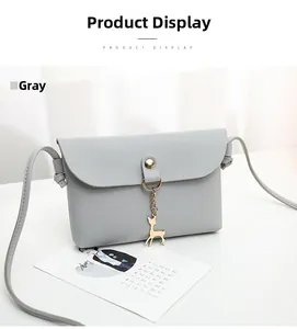 Close-up of gray mini crossbody bag with gold deer charm and magnetic snap button