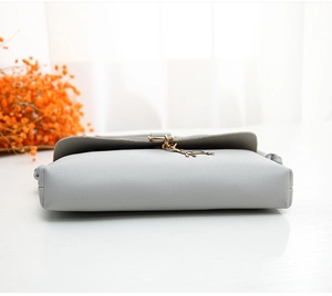 Detail showing the light grey leather bag base with a cute golden puppy charm attachment