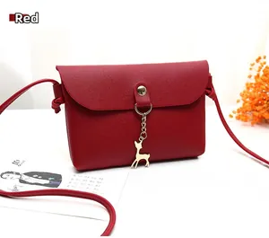 Detail of red small square bag with litchi grain texture and gold deer pendant