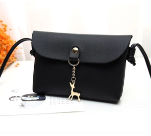 Detail of black pebbled leather crossbody bag with golden deer charm and button closure