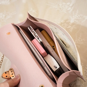 Sac bandoulière rose tendance avec chaîne montrant des compartiments intérieurs spacieux