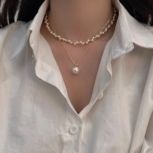 Close-up of double-layer pearl necklace on model with white shirt showing elegant details