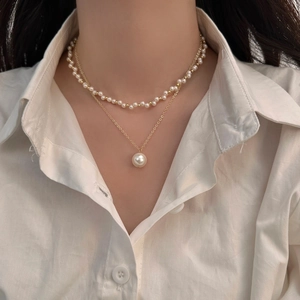 Double-layered elegant pearl necklace featuring a gold chain and vintage-style pendant