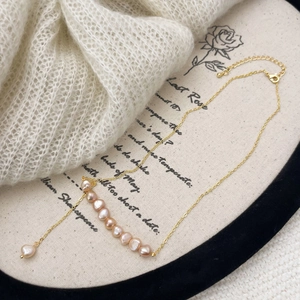 Détail d'un collier de perles d'eau douce roses avec chaîne dorée sur fond vintage esthétique