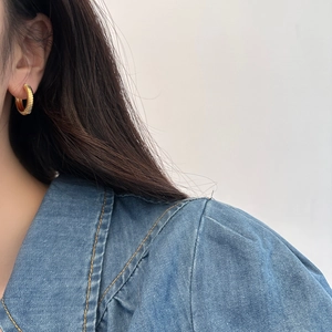 Vintage gold hoop earrings with textured spiral design worn by a model in casual denim