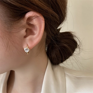 Close-up of elegant gold heart-shaped hoop earrings with a sparkling zircon on model
