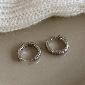 Detailed view of silver hoop earrings with vertical ribbed texture and polished finish