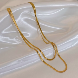 Detail of double-layered gold snake chain necklaces on luxurious white satin silk