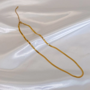 Detail of a gold snake bone chain necklace with lobster clasp on white silk background