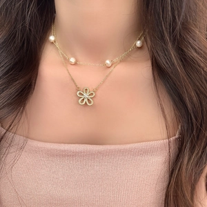 Dettaglio della collana a doppio strato dorata con perle e pendente a fiore micro-incastonato