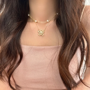 Collana a due strati dorata con pendente a fiore in zirconi e perle d'acqua dolce su modella