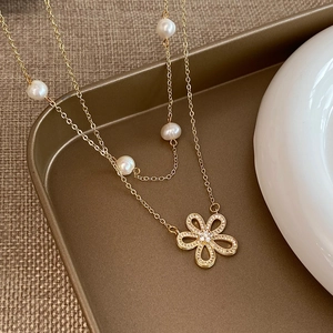 Dettaglio di una collana a doppio strato con perle e ciondolo a fiore in zirconi