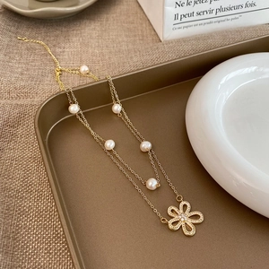 Dettaglio collana a doppio strato dorata con pendente a fiore e perle d'acqua dolce vere
