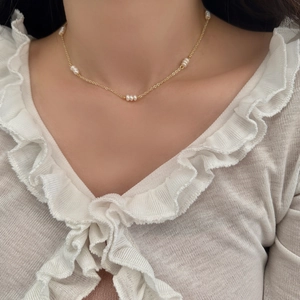 Élégant collier doré avec perles d'eau douce porté sur la clavicule féminine