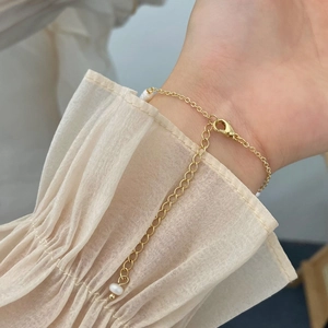 Gros plan d'un bracelet en perles plaqué or avec fermoir mousqueton réglable et extension
