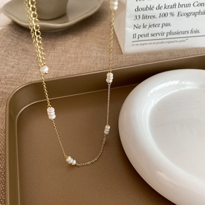 Détail d'un collier en perles d'eau douce style français sur un plateau doré