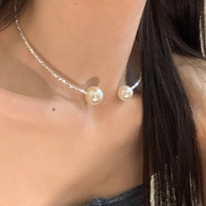 Detailed view of silver minimalist choker with two pearls worn on a female model's neck