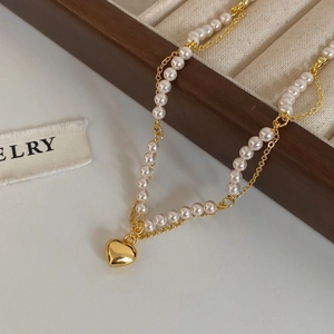 Close-up of gold plated pearl heart pendant necklace on wooden jewelry stand