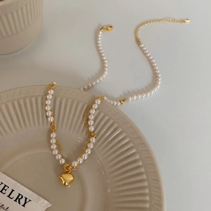 French luxury style pearl necklace with gold heart pendant and layered metal chain