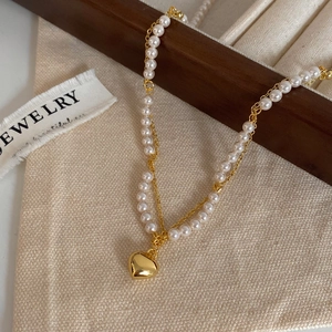 Elegant pearl necklace with golden heart pendant on aesthetic linen background