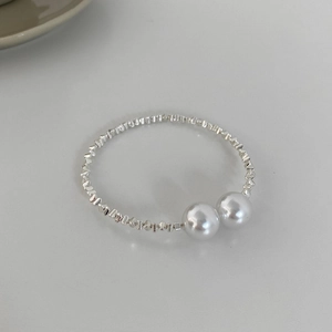 Close-up of elastic silver beaded bracelet with two large pearls in minimalist design