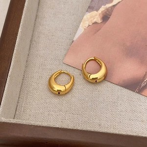 Macro detail of chunky gold teardrop earrings on a textured linen tray display
