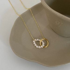 Minimalist gold necklace featuring interlocking pearl and polished metal circular rings