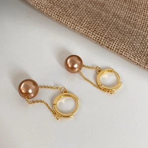 Detail of gold-plated hoop earrings with elegant hanging champagne pearl pendants