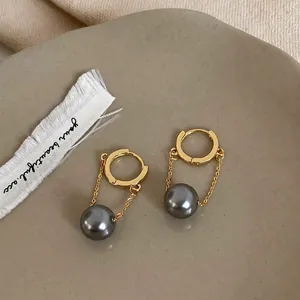 Close-up of gold-plated hoop earrings with elegant dark grey pearl fringe pendants