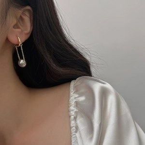 Elegant gold drop earrings with long chain tassel and grey-purple pearl on a model