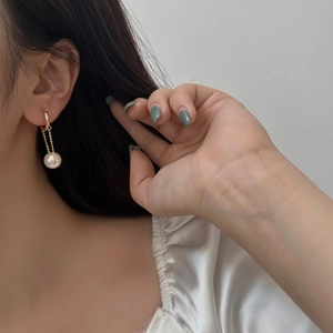Elegant gold dangling earrings with glossy white pearls and delicate link chains