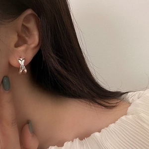 Macro side view of a model wearing minimalist silver S925 cross geometric stud earrings