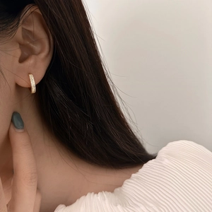 Créoles dorées minimalistes avec zircons scintillants portées par le mannequin
