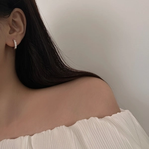 Élégantes boucles d'oreilles créoles avec zircons cubiques portées par un mannequin