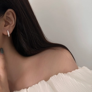 Gros plan de boucles d'oreilles huggie en argent avec zircons sur l'oreille d'un modèle